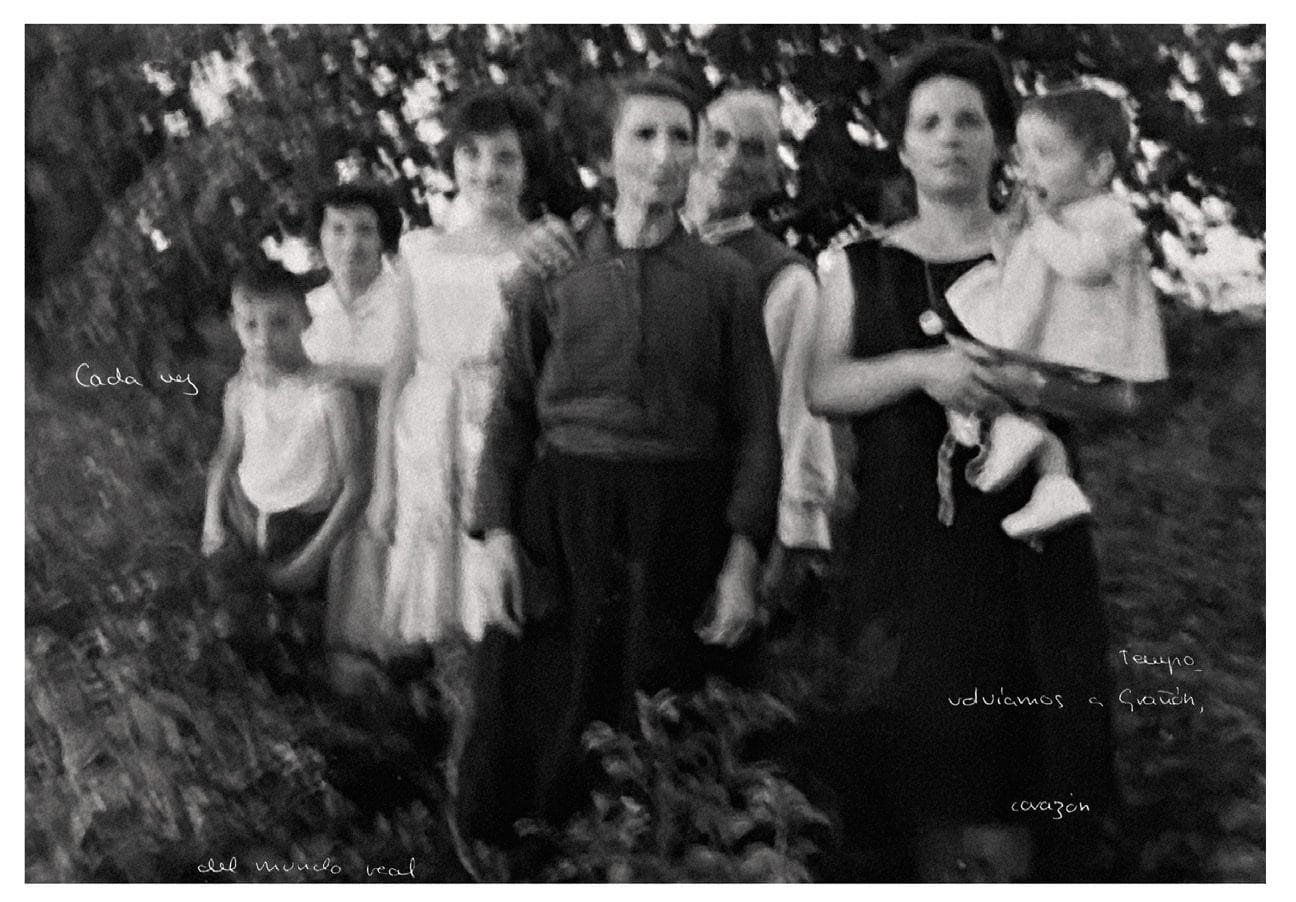 Fotografía en blanco y negro de un grupo de niños y dos mujeres posando ante unos arbustos.